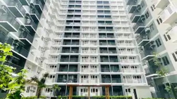 A high-rise residential building with a swimming pool in front.