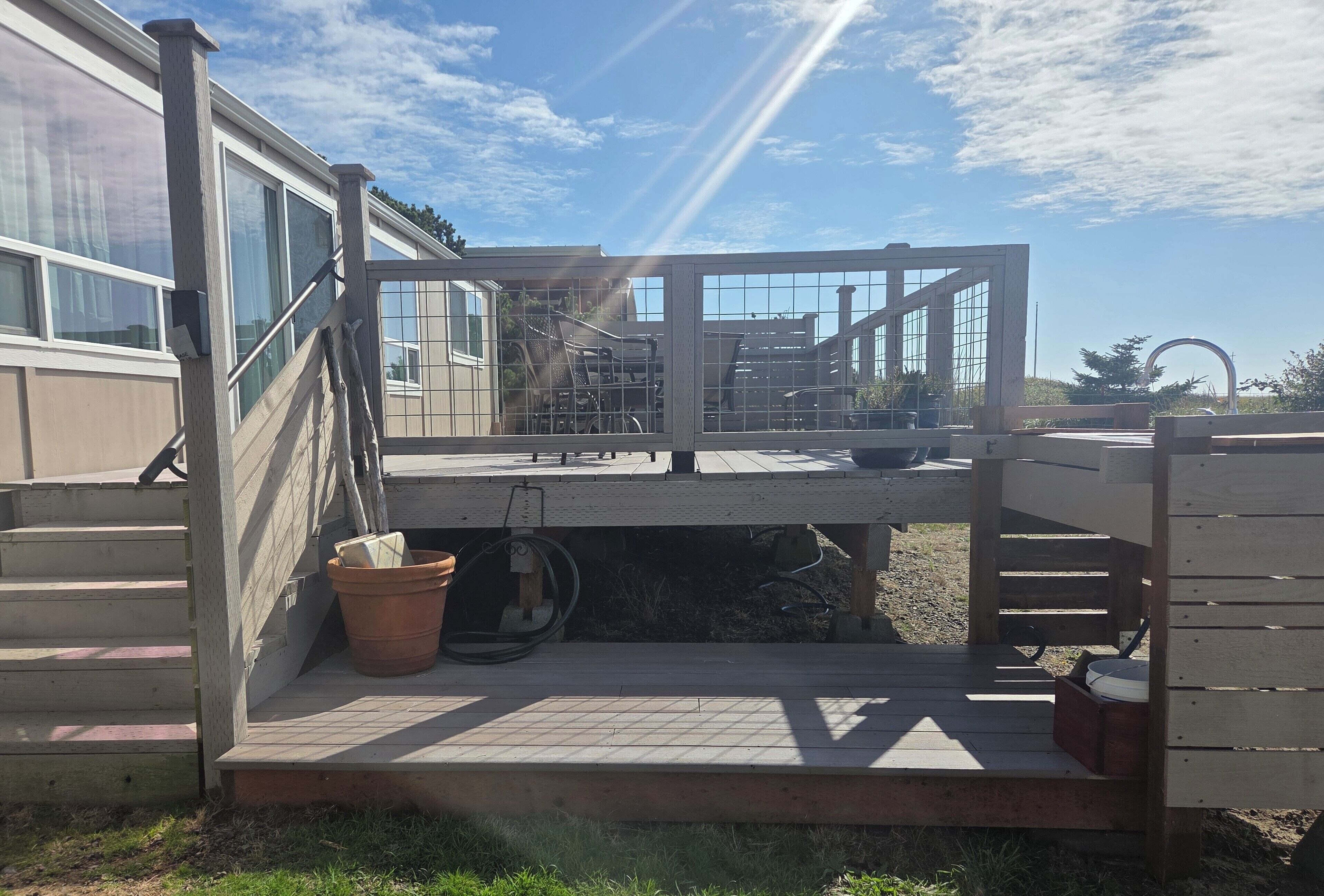 A covered outdoor area with a wooden deck, a metal railing, and a large window.
