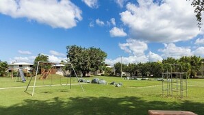 A playground with swings and a slide, a wooden bench, and a metal climbing structure.