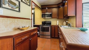 A kitchen with wooden cabinets, a stainless steel stove, a microwave, and a tiled backsplash.
