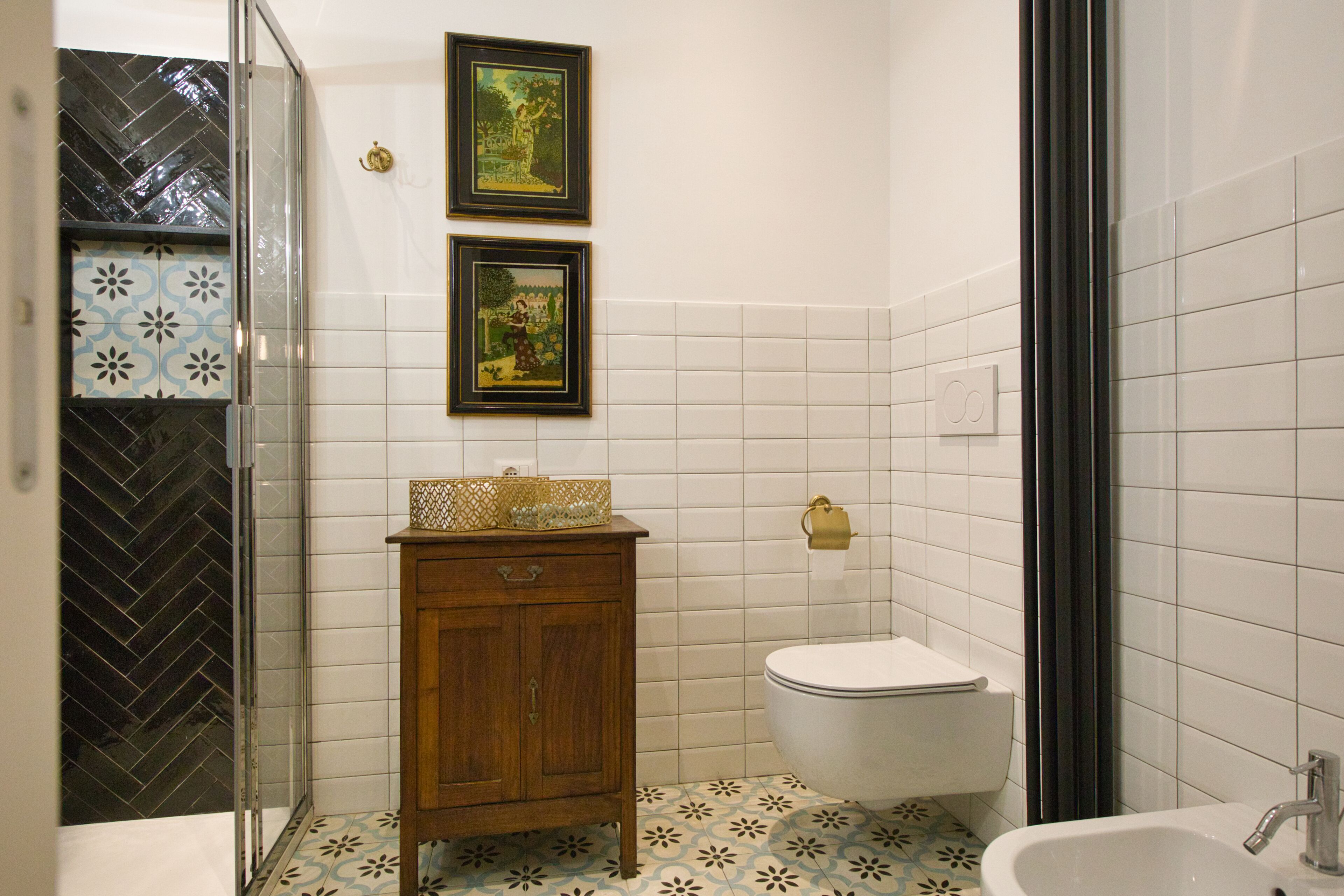 A bathroom with a toilet, sink, and wooden cabinet. There are two framed pictures on the wall.