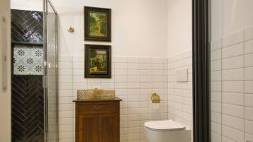 A bathroom with a toilet, sink, and wooden cabinet. There are two framed pictures on the wall.