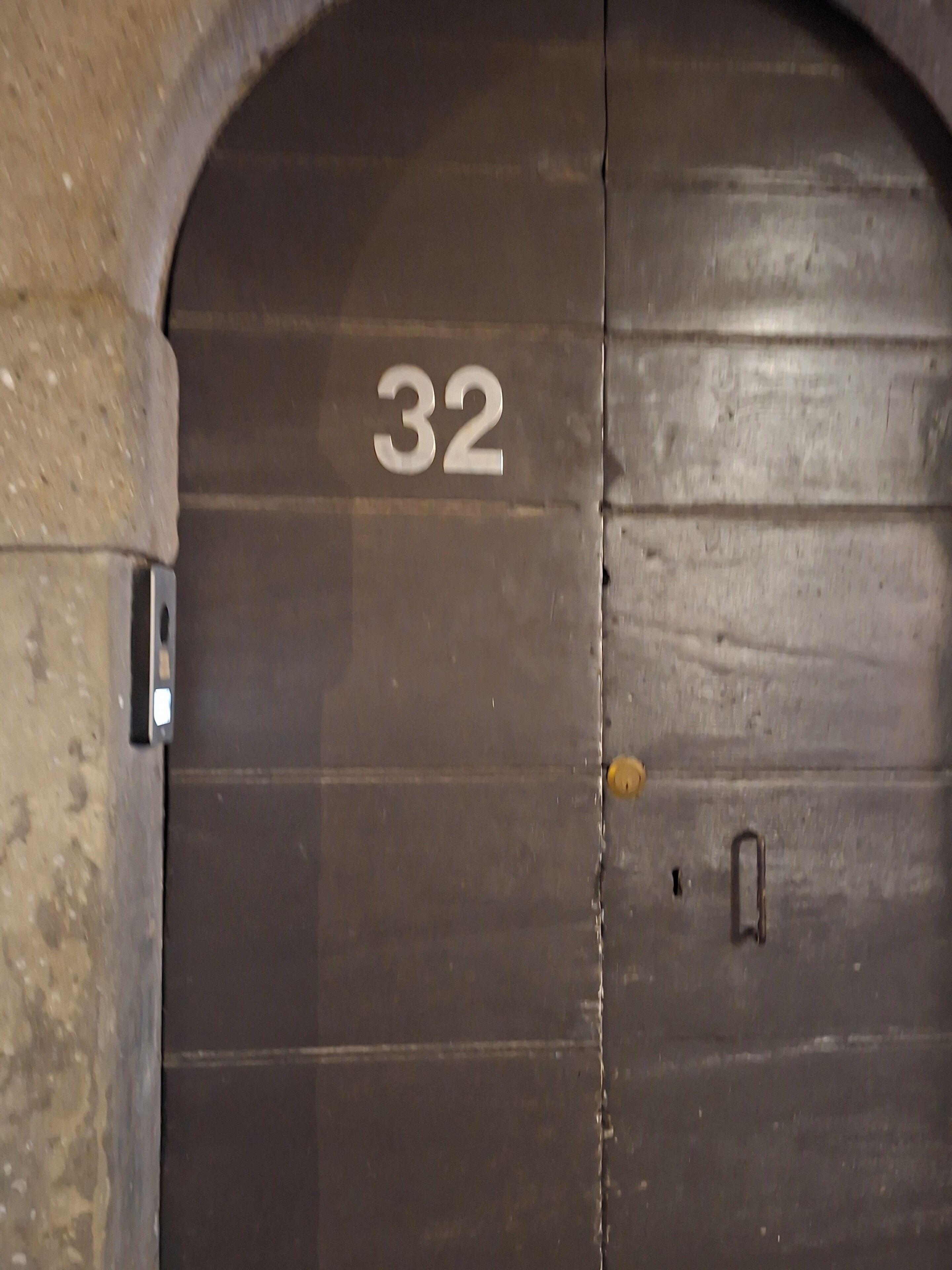 A large, dark wooden door with the number 32 on it, indicating a room or section number.