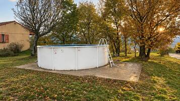 Una piscina amb una escala, envoltada per gespa i arbres.