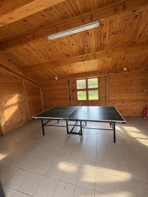 A ping pong table in a room with wooden walls and a tiled floor. - Gîte Petit Pierre Sonnay, Isère (Sonnay)