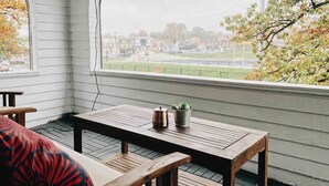 A corner room with a wooden table and bench, a potted plant, and a view of a sports field through a large window. - Rock and Roll House of Fame! 2bed 1bath Central AC (Lakewood)