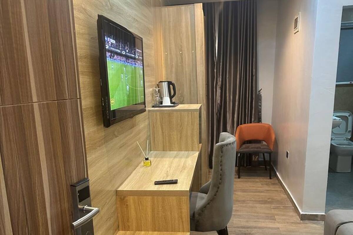 A modern living room with a wooden floor, a sofa, a TV mounted on the wall, and a coffee table.