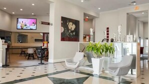 A lobby with a reception desk, seating area, and a television screen.