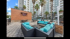 An outdoor patio area with wicker furniture and a brick wall.