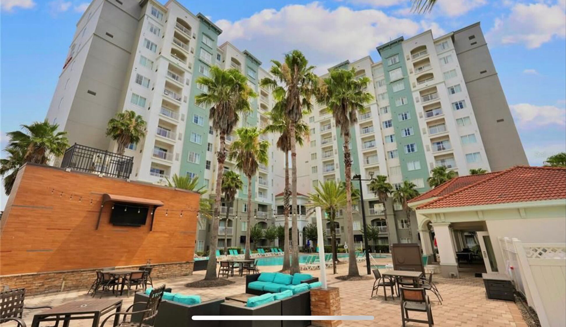 Une cour d’hôtel avec des espaces de détente en plein air, des palmiers et un espace piscine.