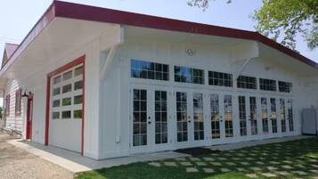 A white building with a red roof, large windows, and a garage door.