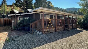 A cabin with a wooden deck, a satellite dish, and a gravel driveway.