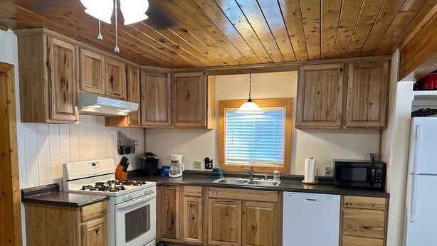 A kitchen with wooden cabinets, a stove, a microwave, and a dishwasher.