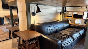 Ein modernes Wohnzimmer mit einem Ledersofa, einem Holztisch und zwei Wandleuchten.