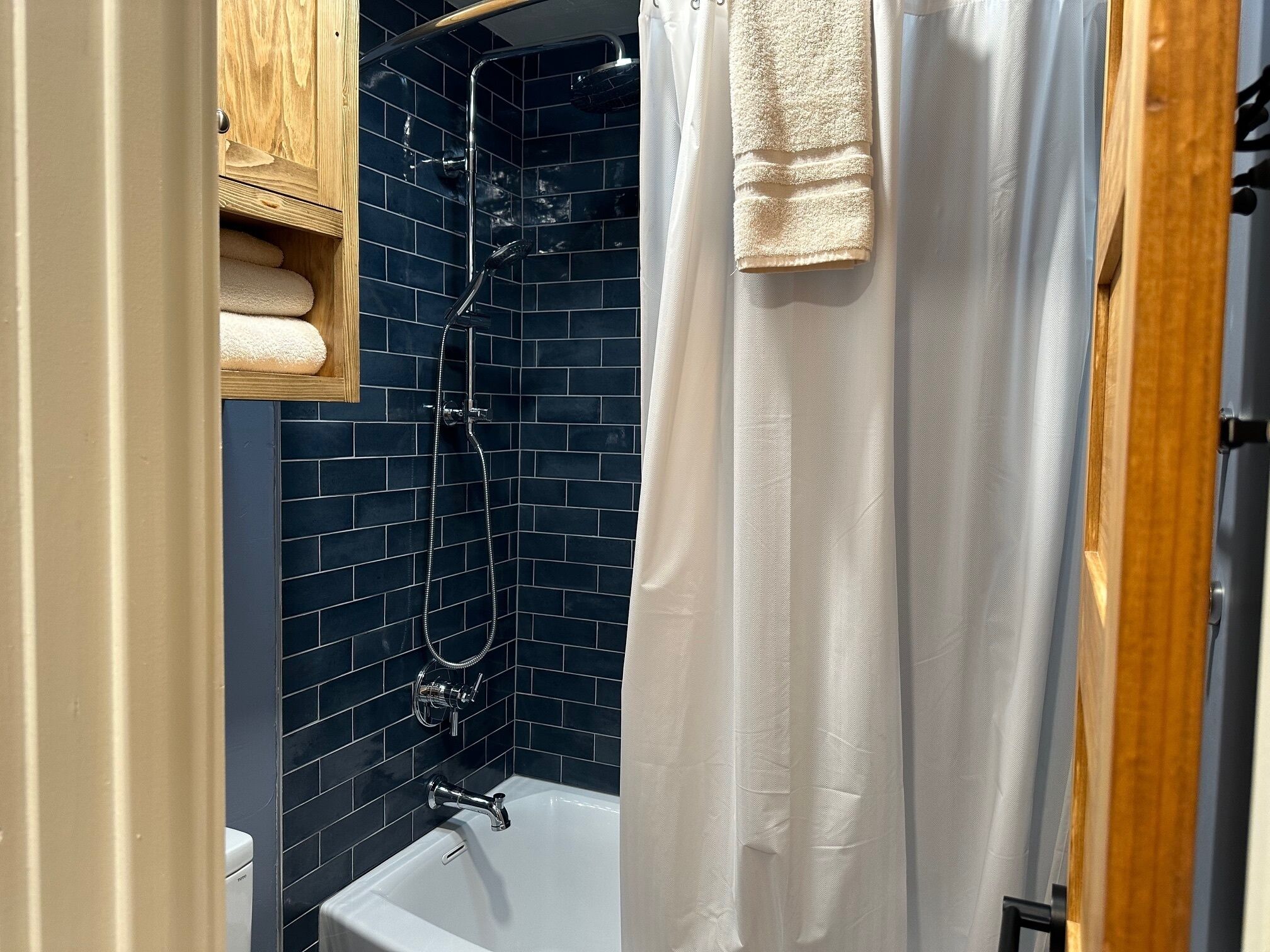 A bathroom with a bathtub, a shower, and a wooden cabinet.