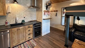 Eine moderne Küche mit Holzschränken, einem Einbauofen und einem Essbereich mit einer schwarzen Ledersofa.