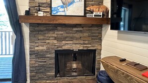 Ein Wohnzimmer mit Kamin aus Stein, einem Wand-Fernseher und gemütlicher Einrichtung.