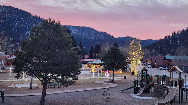 Ein Park mit Spielgeräten, Picknicktischen und Bergblick.