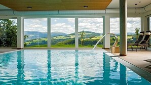 Piscina com vista para colinas verdes e céu claro.