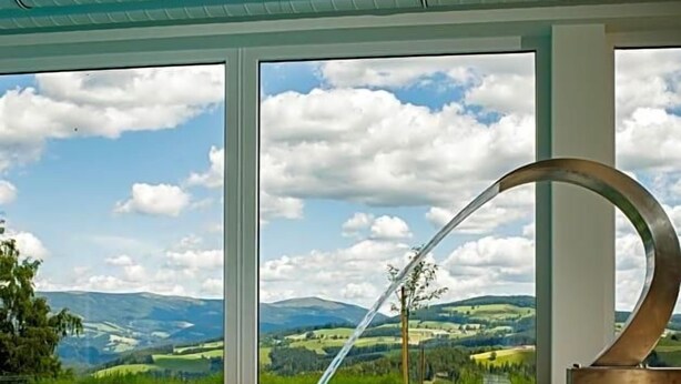 A swimming pool with a clear view of a mountainous landscape through large windows. - Gasthof Almblick (Strallegg)