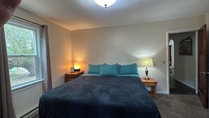 A bedroom with a large bed, two bedside tables with lamps, a window, and a door leading to another room. - Charming 2+ Bedroom private home (Hot Springs)