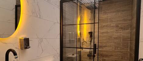 Une salle de bain moderne avec une douche à parois de verre, des toilettes blanches et un lavabo doté d’un plan de travail en marbre.