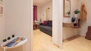 Una sala de estar moderna con un sofá gris, una mesita baja con revistas, un escritorio de madera y un espejo en la pared.