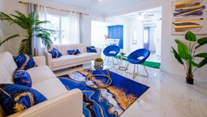 A modern living room with a white sofa, blue and gold patterned rug, and a ceiling fan. - The Blue 4Bedroom Home– Pool & Spa Retreat (North Miami Beach)
