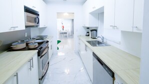 A modern kitchen with white cabinets, a stove, and a sink. - The Blue 4Bedroom Home– Pool & Spa Retreat (North Miami Beach)