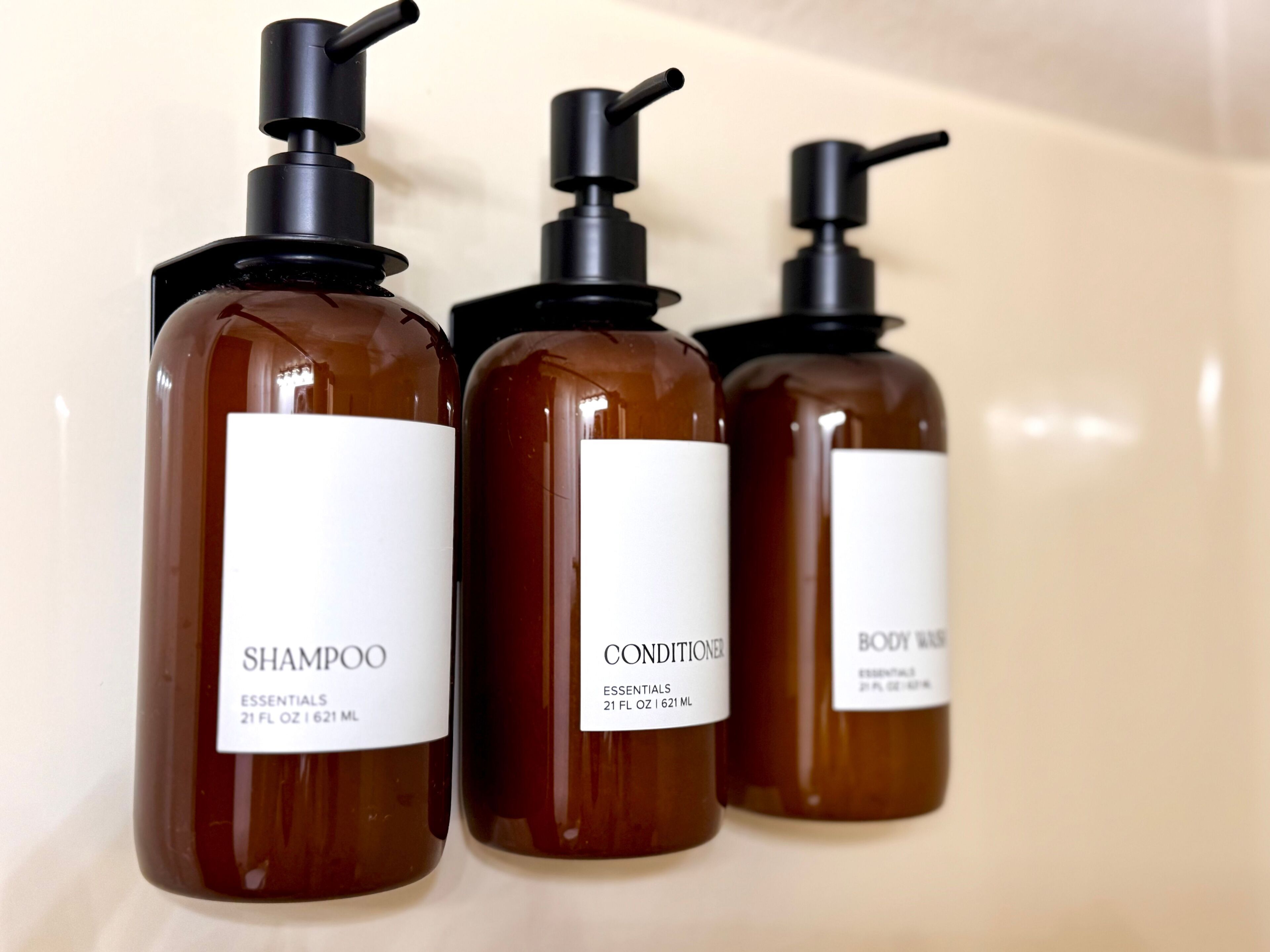 Tre flaskor med produkter för personlig hygien, försedda med pumpar.