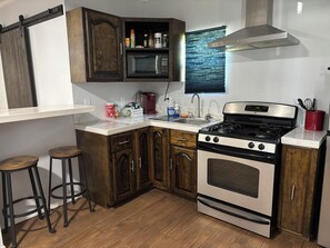Une cuisine avec des meubles en bois, une cuisinière en acier inoxydable, un four à micro-ondes et un évier.