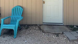 Talo, jossa on valkoinen ovi, sininen muovituoli ja pieni kuisti.