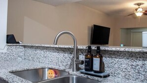 A kitchen with a granite countertop, stainless steel sink, and two bottles of hand soap. - Cozy by Airport & Downtown (Atlanta)