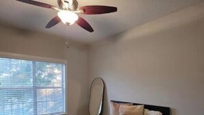 A bedroom with a bed, a nightstand, a ceiling fan, and a window with blinds. - Cozy by Airport & Downtown (Atlanta)