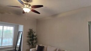 A spacious living room with a large sectional sofa, a ceiling fan, and a large window providing natural light. - Cozy by Airport & Downtown (Atlanta)