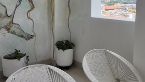 A room with two white wicker chairs, a potted plant, and a mural of birds on the wall. - Apartment in the Historic Center with a great view- BARUC III (Cartagena de Indias)