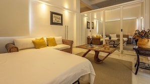 Una habitación de hotel moderna con una cama grande, un sofá, una mesa de comedor y un separador de vidrio.