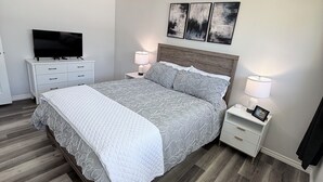 Une chambre moderne avec un grand lit, des tables de chevet, un téléviseur à écran plat et des œuvres d’art abstraites accrochées au mur.