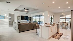 A modern kitchen with a central island, white cabinetry, and a large window providing natural light.