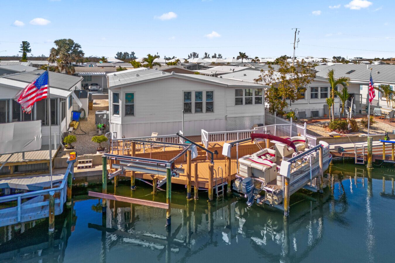 A marina with several boats docked, a wooden dock, and a white building with an American flag.