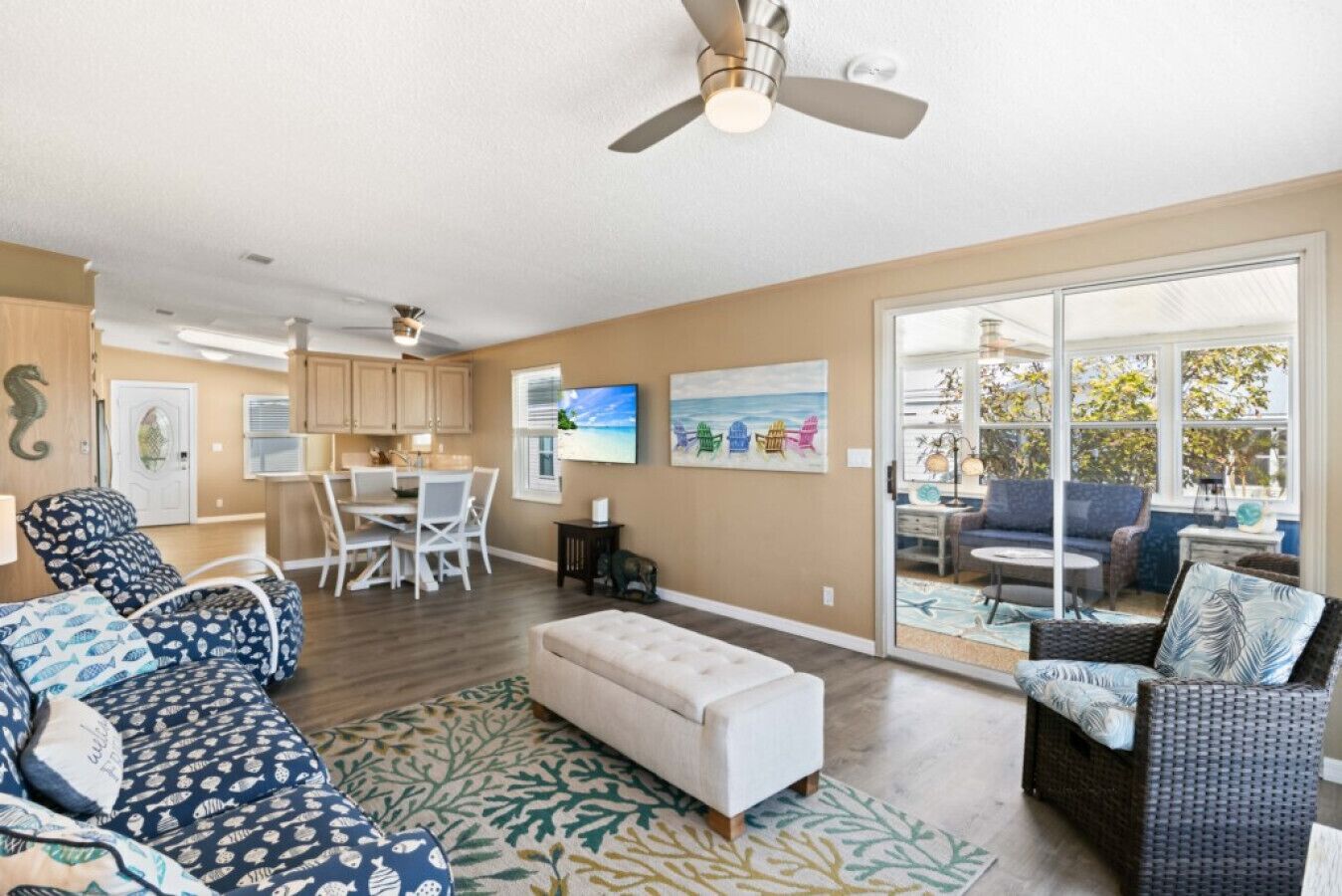 A spacious living room with a large sofa, a dining area, and a view through a sliding glass door to an outdoor patio.