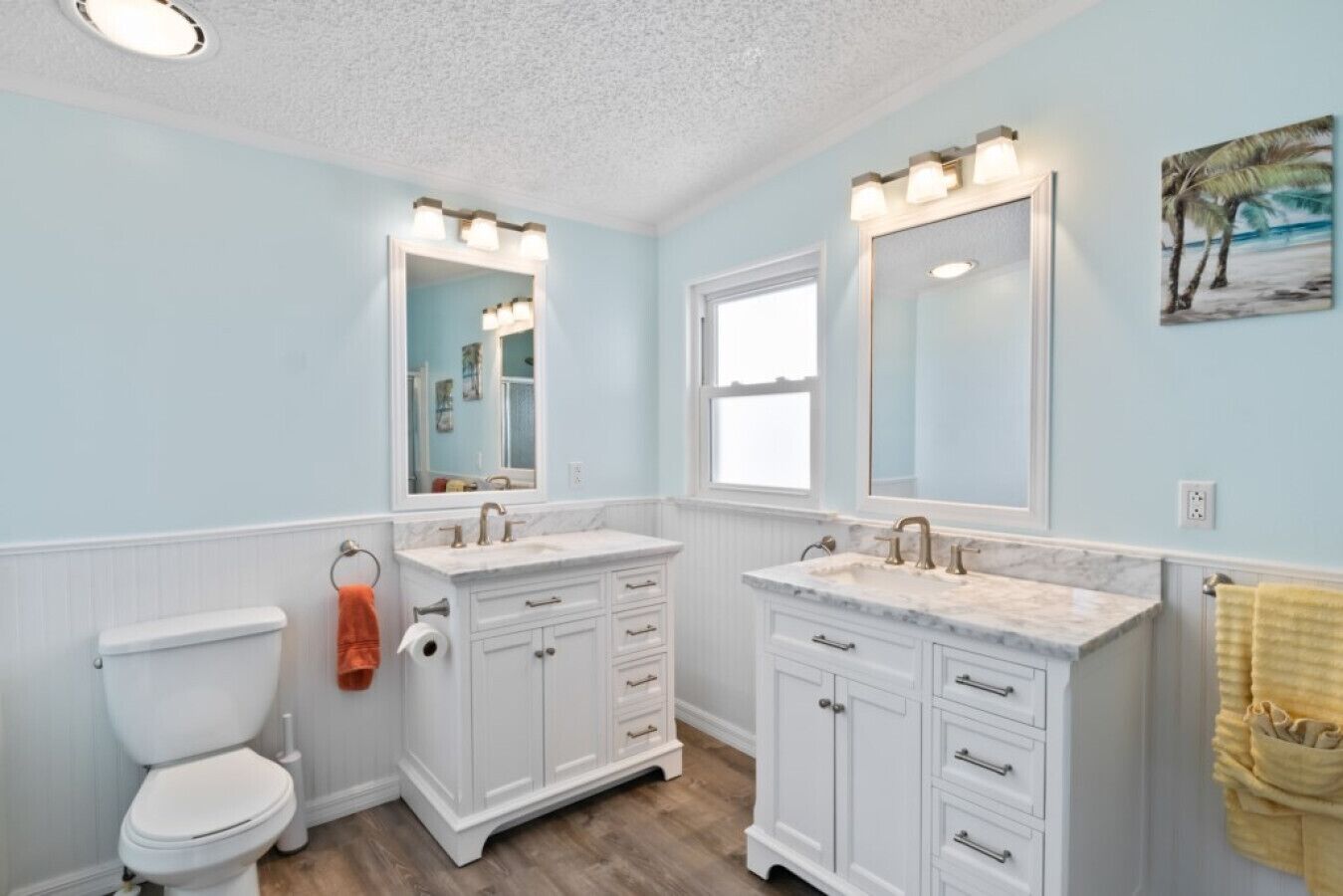 A bathroom with two sinks, a toilet, and a mirror.
