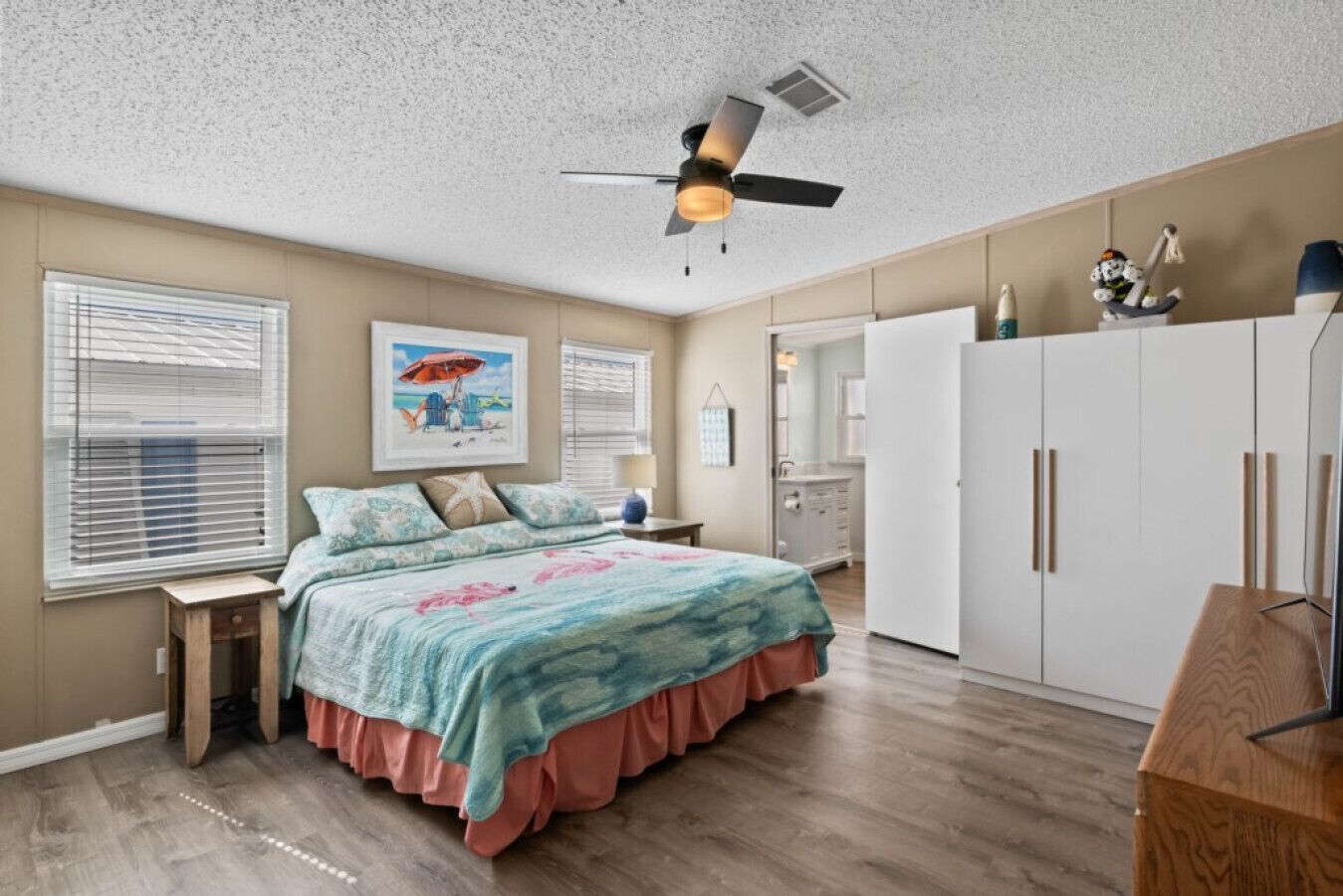 Un dormitorio con cama, ventilador de techo, armario y ventana con persianas.