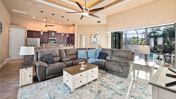 A spacious living room with a large sectional sofa, a coffee table, and a view of the backyard through large windows.