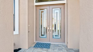 A double door with a glass panel and a welcome mat in front.