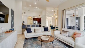 A spacious living area with two white sofas, a coffee table, and a kitchen in the background. - Beautiful Pool Home with Gulf access (Cape Coral)