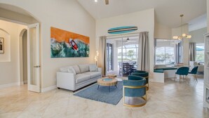 A spacious living room with a large sofa, a coffee table, and a painting on the wall. - Beautiful Pool Home with Gulf access (Cape Coral)