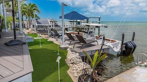 A boat docked at a marina with lounge chairs and umbrellas. - Coastal Charmer  Direct Gulf-Front Getaway in the Florida Keys (Long Key)