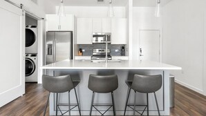 A modern kitchen with a central island, stainless steel appliances, and a built-in washer and dryer.