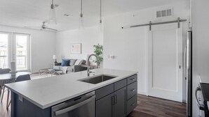 Une cuisine moderne dotée d’un grand îlot central, d’appareils électroménagers en acier inoxydable et d’un placard à portes coulissantes.